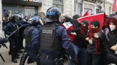 EPA/Shutterstock Masked students face riot police in full armour in the streets